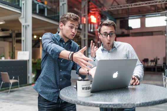 zwei Leute schauen erstaunt auf MacBook