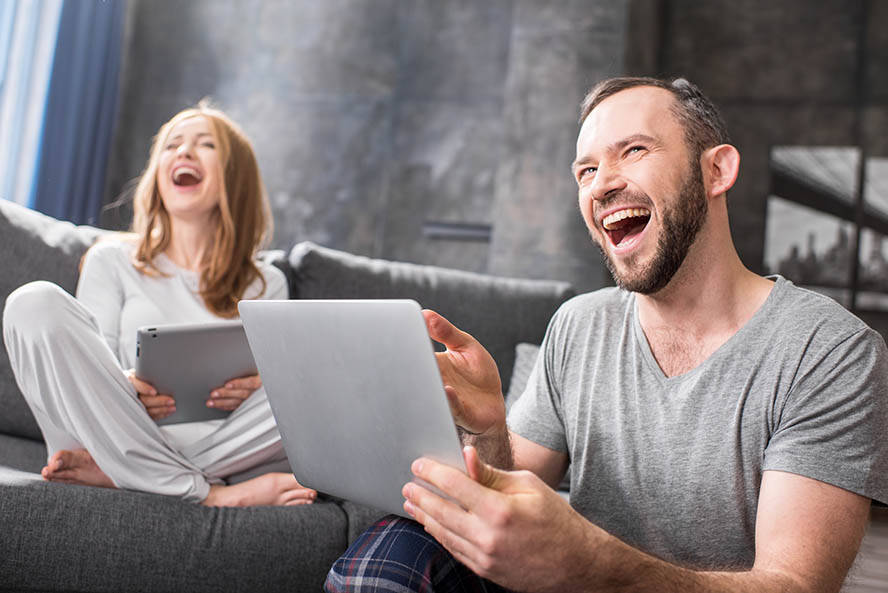 Young couple using digital devices and laughing