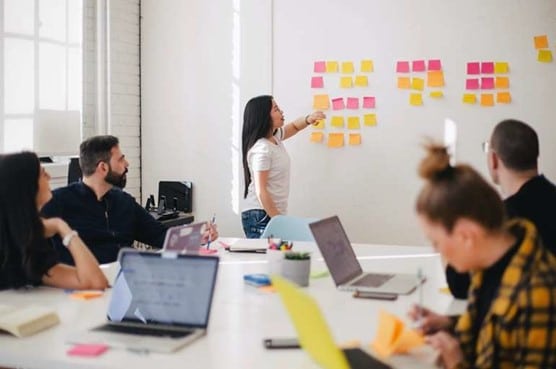 Meeting, bei dem eine Person vor den anderen steht und präsentiert