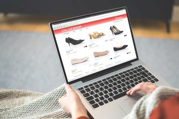 Produktseiten optimieren Stockfoto Laptop in den Haenden mit geöffneter Schuh-Onlineshop-Website