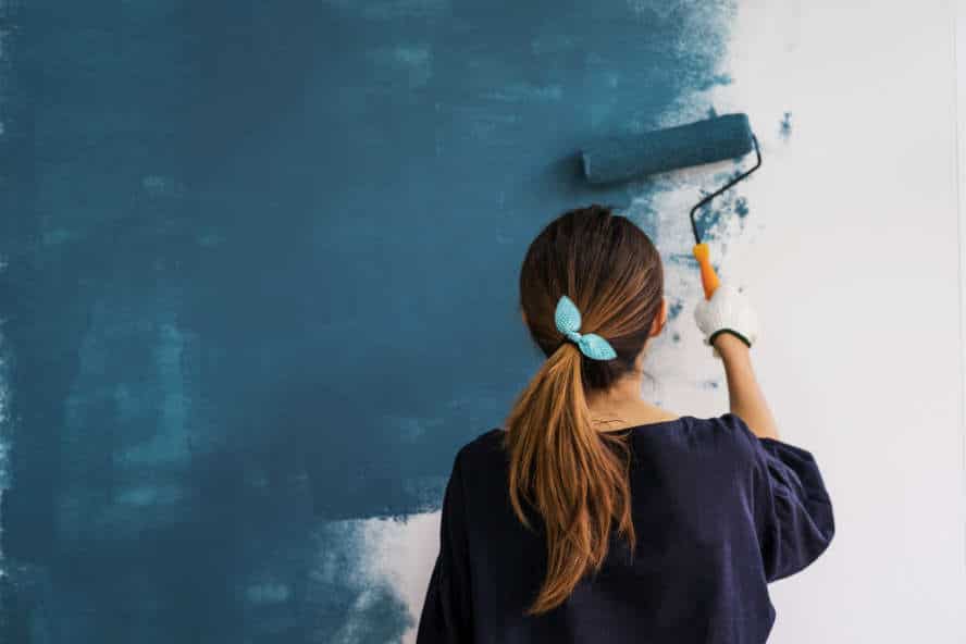 Frau streicht eine Wand neu